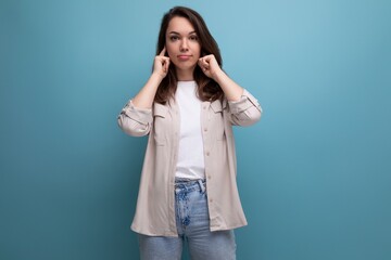 Fototapeta premium European model appearance young dark-haired lady in informal clothes closed her ear on a blue background