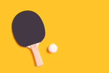 Tennis racket and white ball on a yellow background. Lifestyle concept with copy space.