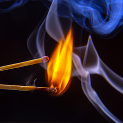 Flashed and burning wooden match on a dark background close-up. Bright fire and smoke from a...