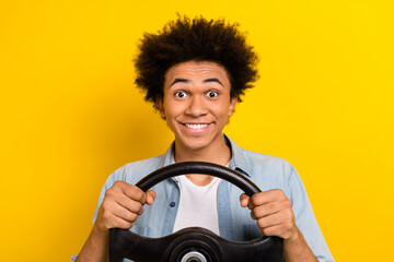 Photo of excited cheerful guy dressed denim shirt riding automobile isolated yellow color background