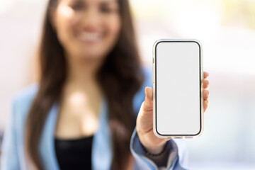 Smiling holding mobile phone showing blank white screen, selective focus, mockup. Happy female using mobile app shopping online, ordering food on website. Technology concept