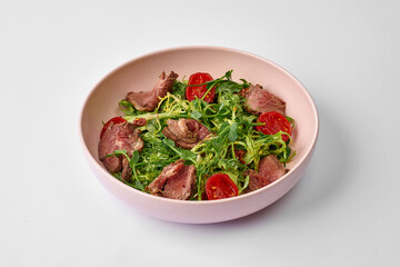 Salad with roast beef and sun-dried tomatoes in a plate.