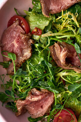 Salad with roast beef and sun-dried tomatoes in a plate. - obrazy, fototapety, plakaty