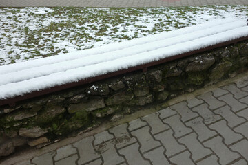 Fototapeta premium Concrete wooden bench covered with snow