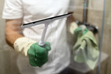 Window glass wiper in male hands, cleaning service concept. - obrazy, fototapety, plakaty