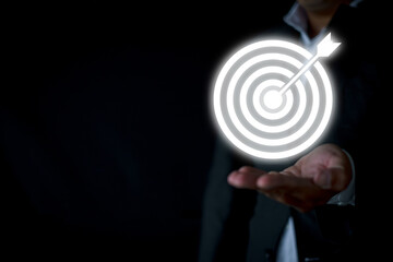 Businessman shows a palm up gesture with dartboard target icon over black background with copyspace suitable for Business Goal and Objective Target,Achievement and Purposefulness,challenge idea.