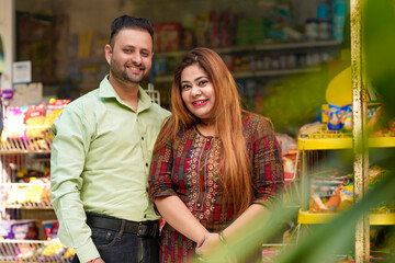 Happy Indian couple standing at grocery shop.