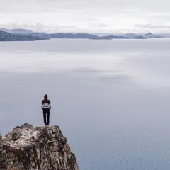 Fotobehang girl on a cliff with a huge lake in the background © Benedikt_Dover
