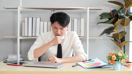 Young asian businessman feeling sleepy after working long time. Yawning during working, Exhausted businessman working hard overtime 