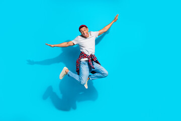 Fototapeta na wymiar Full size portrait of energetic overjoyed man jumping arms wings flying empty space isolated on blue color background