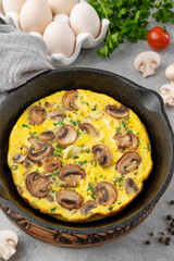 Omelette with mushrooms and herbs in a pan on a white wooden background. Healthy breakfast. Top view. Copy space.