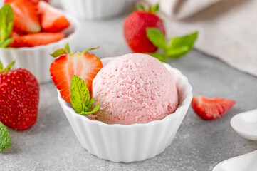 Strawberry ice cream with fresh berries in a bowl on a gray concrete background. Selective focus