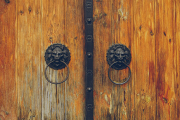 Decoration of wooden gates. Knocker in the form of lion heads with rings in the mouth. Close-up.