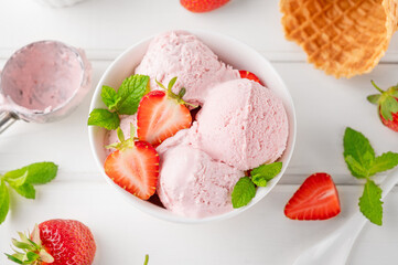 Strawberry ice cream with fresh berries in a bowl on a white wooden background. Selective focus