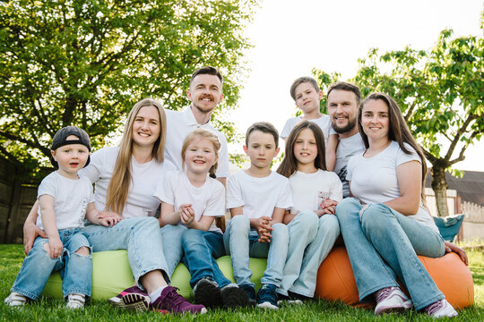 Family photo of one big happy family with children in nature. Nine people outdoors. Friends relax in the backyard. Big family garden party celebration, gathered together.  People with kids having fun.