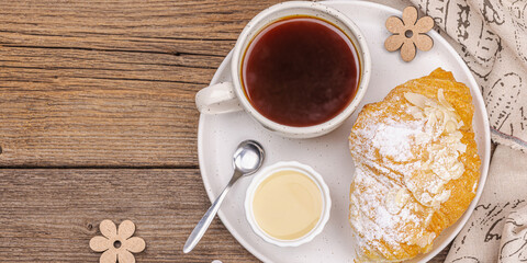 Good morning concept. Breakfast with cup of coffee and fresh croissant. Sweet creamy sauce
