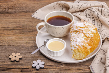 Good morning concept. Breakfast with cup of coffee and fresh croissant. Sweet creamy sauce