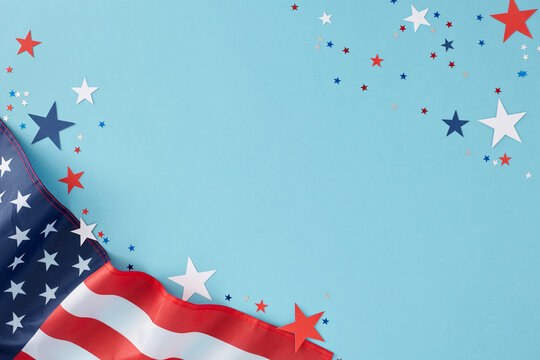Creating a memorable party theme for American Independence Day. Top view flat lay of american flag and star-shaped confetti on pastel blue background with empty space for text or promotion
