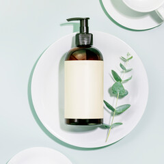 Mockup of natural dish detergent. Eco friendly cleaning dishes. Bottle with organic dish detergent on clean plate on blue background with sprig of eucalyptus. Flat lay