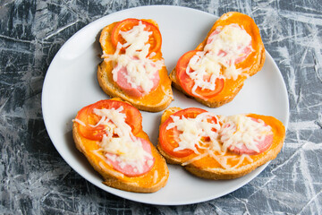 Delicious hot sandwiches with sausage, cheese and hot sauce, on white bread, on a gray plate