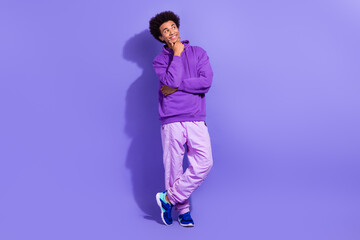 Full size photo of ponder pensive person wear violet hoodie sport pants look at empty space offer isolated on purple color background