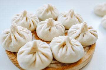 Khinkali sprinkled with flour on round wooden board