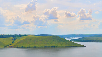 Summer river flowing among flowering green hills and sunny clouds