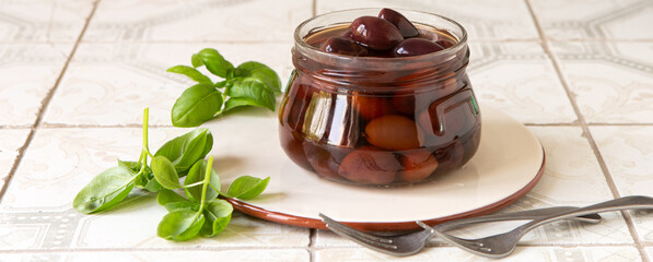 glass jar with greek kalamata olives on light table