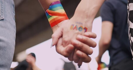 A couple's hands with a rainbow tattoo sticker representing the symbol of homosexuality in a pride parade. - Powered by Adobe
