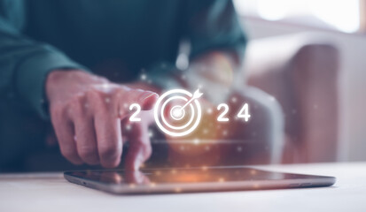 2024 business planning and strategy concept, businessman pointing virtual icon of  year 2024 target  working on smartphone, marketing financial and research analysis, investment trends next new year