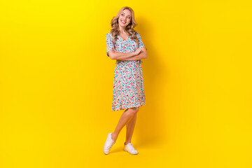 Full length photo of shiny thoughtful woman dressed flower print sarafan arms crossed looking empty space isolated yellow color background