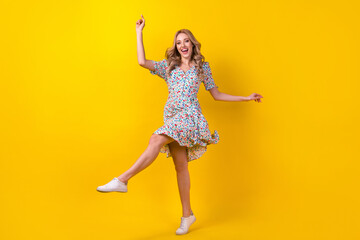 Fototapeta na wymiar Full length photo of positive cheerful lady wear flower print dress having fun dancing isolated yellow color background