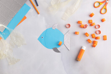 Paper adorable fish with children at home. Hands making DIY summer crafting. Ocean's day. 