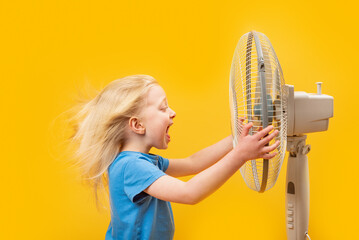 Little blond girl with move in wind hair holding stand fan and screaming. Child and air circulator...