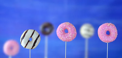 Zelfklevend Fotobehang row of sweet donuts, some blurred in the background, snacks, sweets and junk food concept, free copy space © Kirsten Hinte