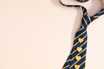 Father's Day concept. Flat lay top view of necktie and hearts on pastel beige background with space for text or promotion and greeting message, banner