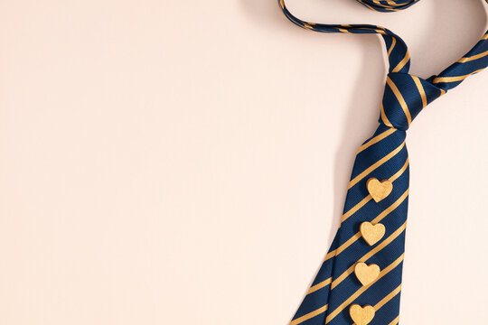 Father's Day concept. Flat lay top view of necktie and hearts on pastel beige background with space for text or promotion and greeting message, banner