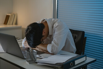 Tired Asian business man falling asleep at table Alone Working holding his head on hands after late night work. asian male employee