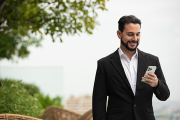 Portrait of handsome businessman outdoors at rooftop using phone
