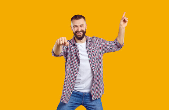 Happy excited magnificent bearded man 30s years old wears plade shirt pointing finger up on workspace area. Confident man fist bump showing her support. Isolated image in btight yellow backgrouns.