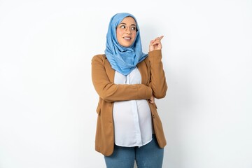 Photo of attractive Young beautiful pregnant muslim woman wearing hijab in white studio direct finger empty space cheap dentistry