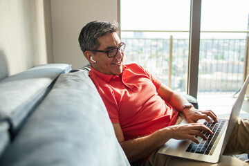 Middle aged hispanic man using a laptop at home
