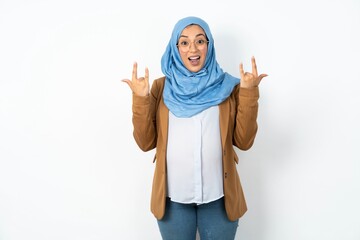 Young beautiful pregnant muslim woman wearing hijab over white background makes rock n roll sign...
