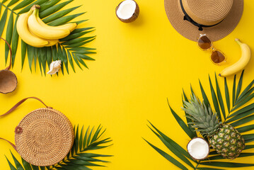 Savoring the allure of summer. Top view of beach must-haves, purse, glasses, sunhat, palm leaves, and tantalizing exotic fruits on a vibrant yellow backdrop with frame for text or advertorial content