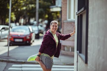 Middle aged man stretching before a workout in the city