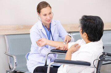 Fototapeta premium Female doctor caring for an elderly woman patient sitting in a wheelchair.