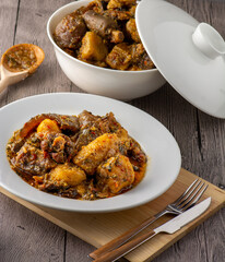 Efik delicacy Unripe plantain porridge served with oxtail on a plate from a white ceramic bowl