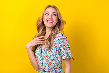 Photo of adorable dreamy lady wear flower print dress smiling looking back empty space isolated yellow color background