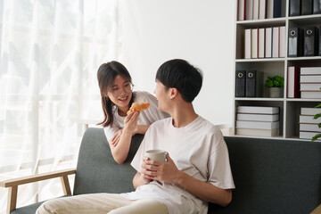 Fototapeta premium Beautiful asian couple in love and smiling sitting on sofa at morning. Romantic moment, relationships, family concept