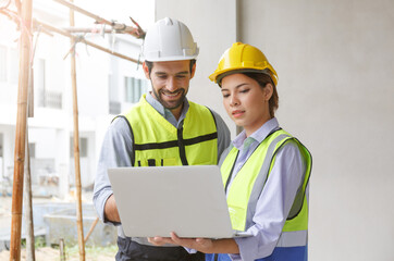 Team of industrial engineers men and women wearing helmets discussing new projects. while using laptop